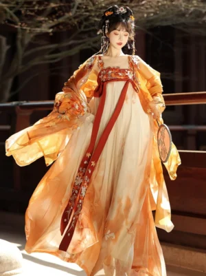 Front view of a flowing Tang Dynasty Hanfu dress with sheer orange outer robe, floral embroidery, wide sleeves, and long red decorative sash in a traditional courtyard