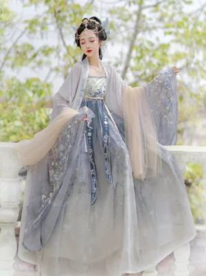 Blue Tang Dynasty Hanfu Heziqun dress set worn by model outdoors, featuring a beige wrap dress, flowing wide sleeve coat, embroidered waist sash and elegant layered silhouette