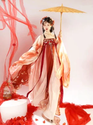 Three-quarter view of a Tang Dynasty style Hanfu Heziqun dress with red and light pink layers, embroidered waist detail, flowing coat, and yellow oil-paper umbrella