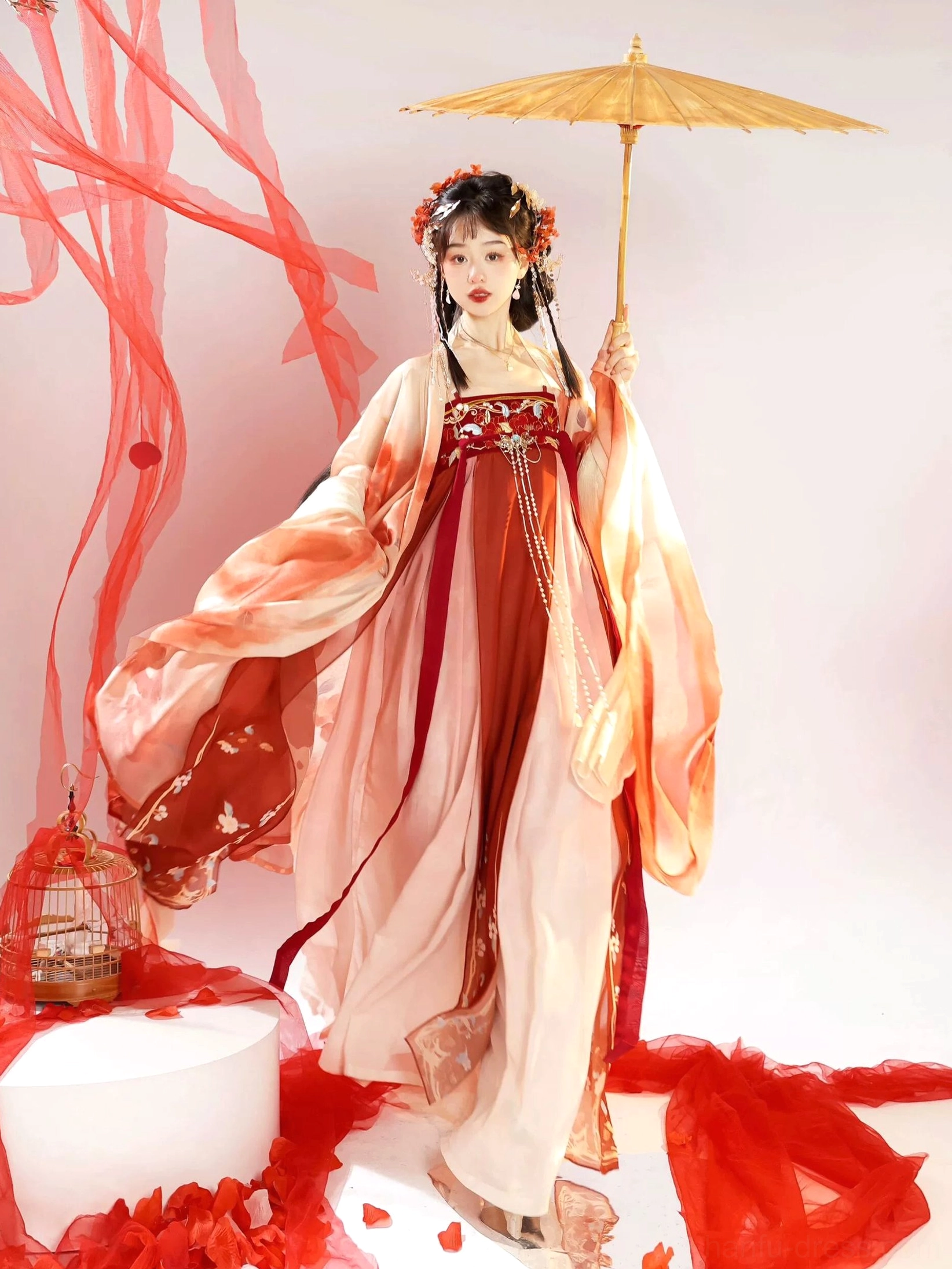 Three-quarter view of a Tang Dynasty style Hanfu Heziqun dress with red and light pink layers, embroidered waist detail, flowing coat, and yellow oil-paper umbrella