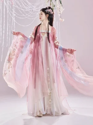 Left side full body view of a Tang Dynasty Hanfu Heziqun dress set with dusty pink floral embroidered wide sleeve coat, flowing gradient skirt, and light blue waist sash