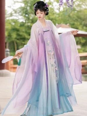 Side three quarter view of a Tang Dynasty style Qixiong Ruqun Hanfu with gradient purple white cyan fabric floral skirt decoration wide sleeves and handheld tassel fan in a Chinese garden