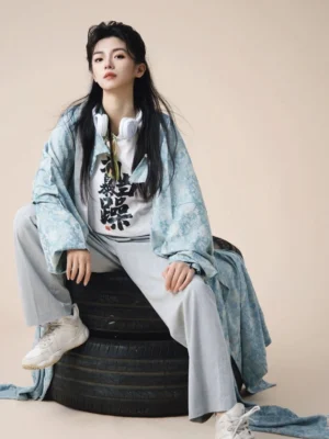 Full-body view of a flowing Tang Dynasty inspired Hanfu robe with long sleeves and relaxed silhouette styled with contemporary sneakers in a neutral studio