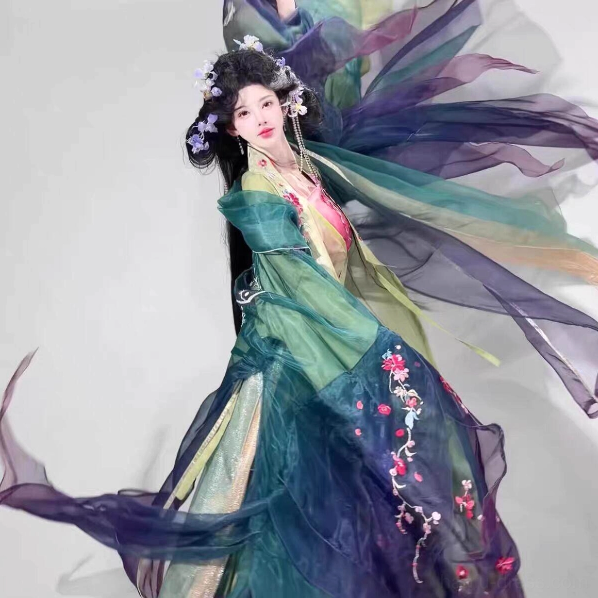 Side view of flowing Tang Dynasty hanfu set showing dark teal outer robe, pink flower embroidery, and layered purple green fabric
