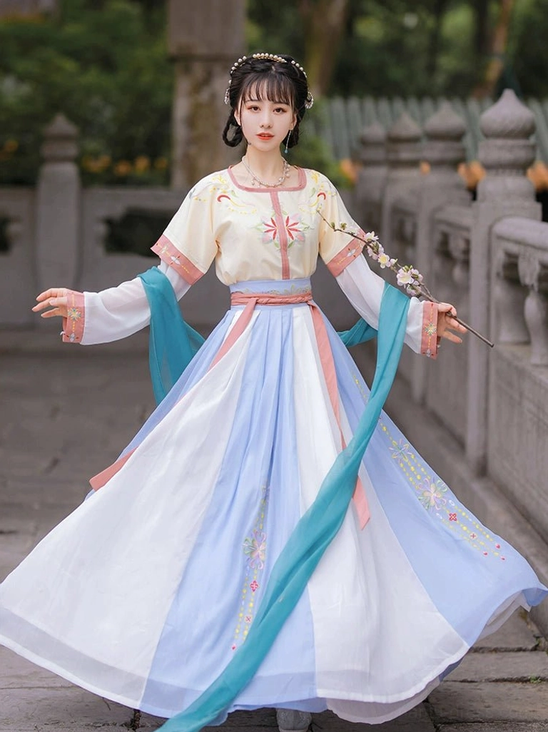 Front full-body view of a Tang Dynasty style U-collar Qiyao Ruqun Hanfu set in cream yellow, pink, white, light blue, and cyan with floral embroidery in a traditional Chinese courtyard