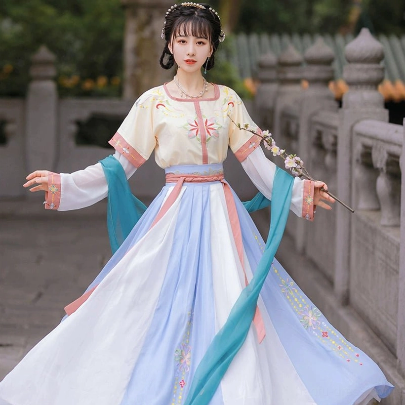 Full front view of a cream yellow and pink Tang Dynasty Qiyao Ruqun Hanfu with a voluminous color-block skirt, floral embroidery, and flowing cyan sash