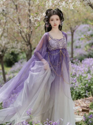 Front view of a Tang Dynasty Hezi Hanfu dress with purple to ivory gradient skirt, embroidered bust top, gold waist chains, and sheer wide sleeve jacket in a flowering garden