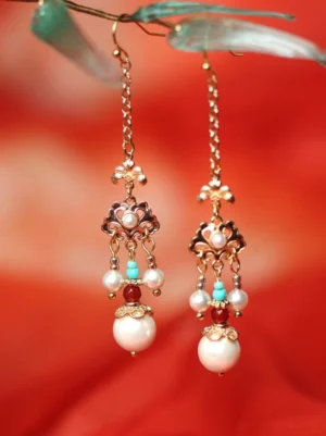 Tang Dynasty inspired Chinese Hanfu earrings with gold floral filigree, pearl tassels, turquoise beads and red accents on red satin background
