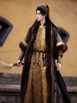 Full-body side view of a male Tang Dynasty Hanfu outfit with gold jacquard round-collar robe, dark fur-trimmed coat, black multi-strap waist belt, and ornate metal wrist guards in a traditional Chinese courtyard