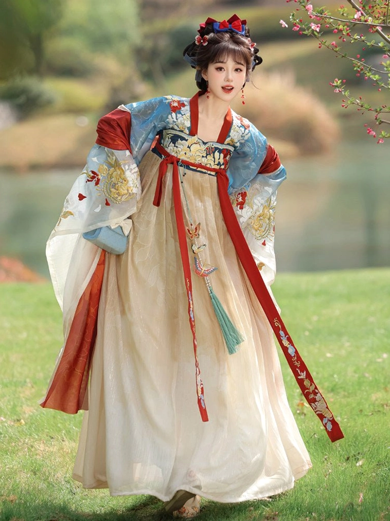 Front three-quarter view of Tang Dynasty Hanfu with golden floral embroidery, flowing blue sleeves, cream pleated skirt, red shoulder ribbons, and green tassel waist pendant