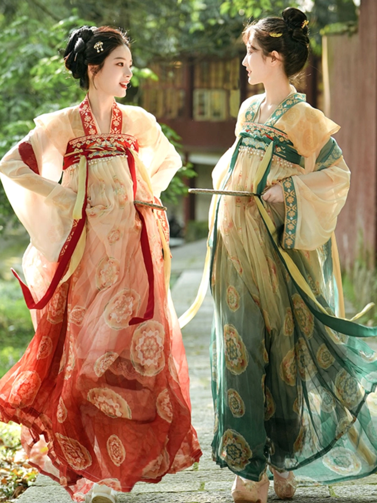 Side view of two Tang Dynasty Qixiong Ruqun Hanfu dresses in red-beige and green-beige with matching sashes in an ancient Chinese courtyard