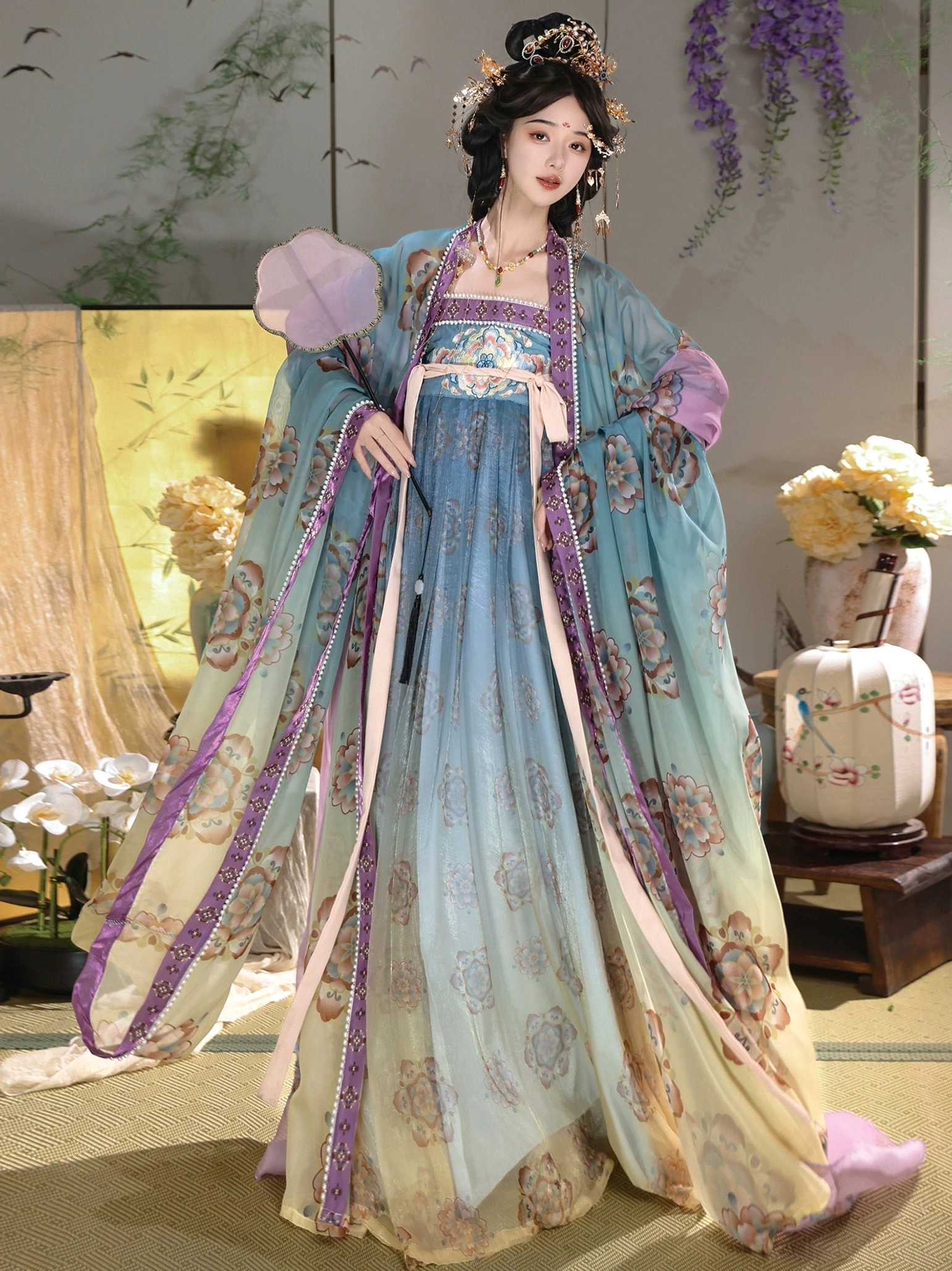 Front view of colorful Tang Dynasty hanfu Qixiong Ruqun with flowing teal outer sleeves, floral dress, and traditional pink hand fan