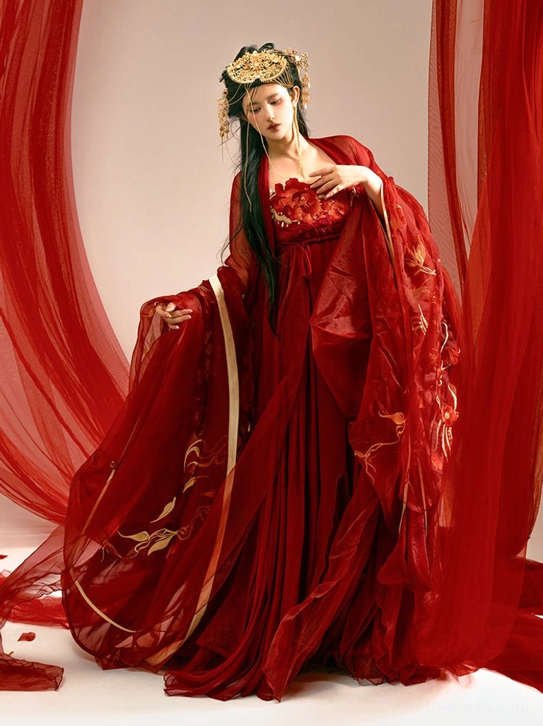 Three-quarter front view of a deep red Tang Dynasty style Hanfu Heziqun wedding dress with golden floral embroidery, off-shoulder bodice, wide sleeves, and traditional Chinese bridal hair ornaments