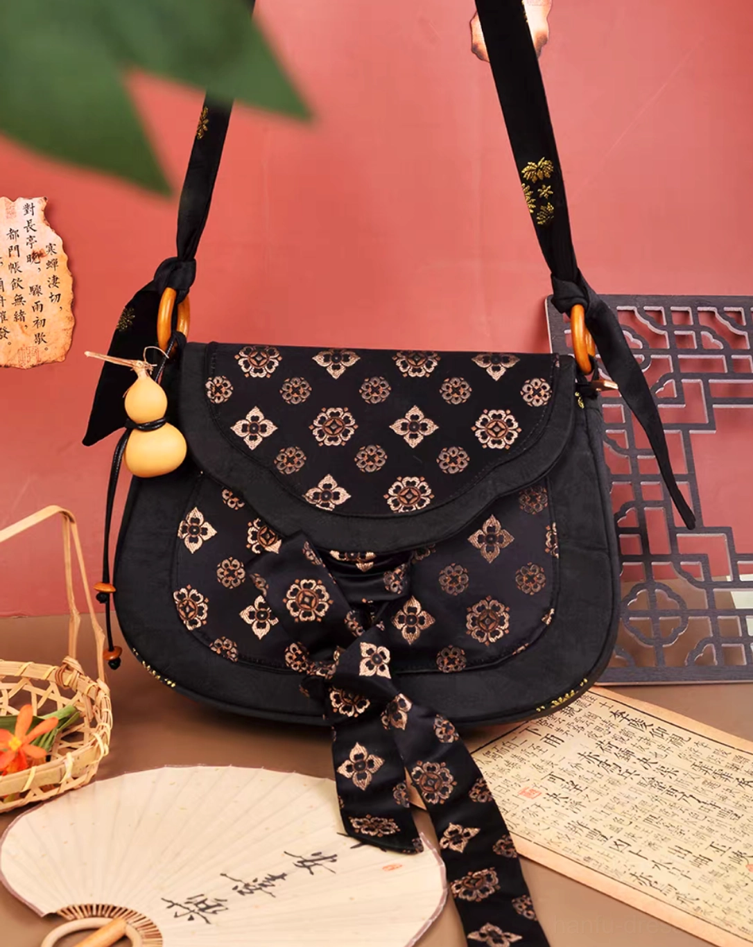 Tang Dynasty vintage Chinese shoulder bag held by hand showing black floral brocade fabric, bamboo style hardware and gourd pendant