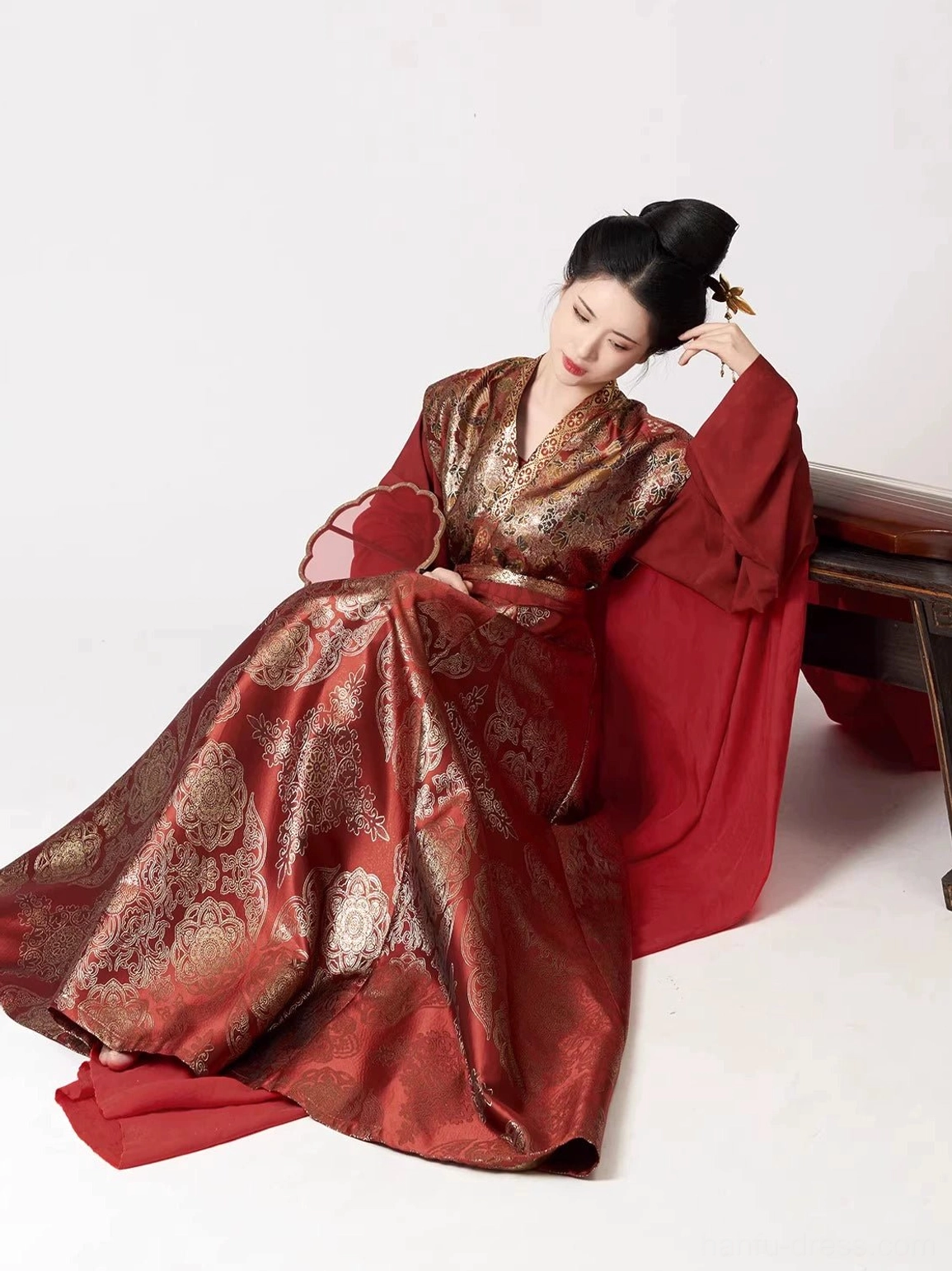 Seated model wearing Tang Dynasty wine red Hanfu set with gold motifs and elegant eight-panel skirt spread
