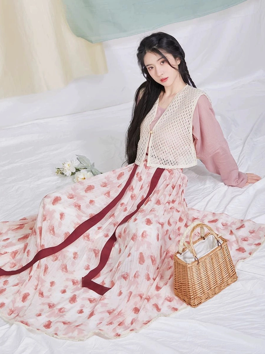 Side seated view showing the layered dusty pink hanfu top, beige crochet beizi, raspberry-print skirt, and wine-red sash