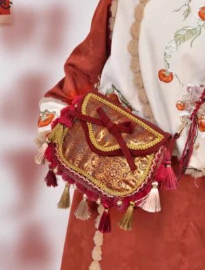 Traditional Chinese tassel crossbody bag worn at the waist with embroidered Hanfu, featuring burgundy trim, brocade flap, gold lace and colorful tassels