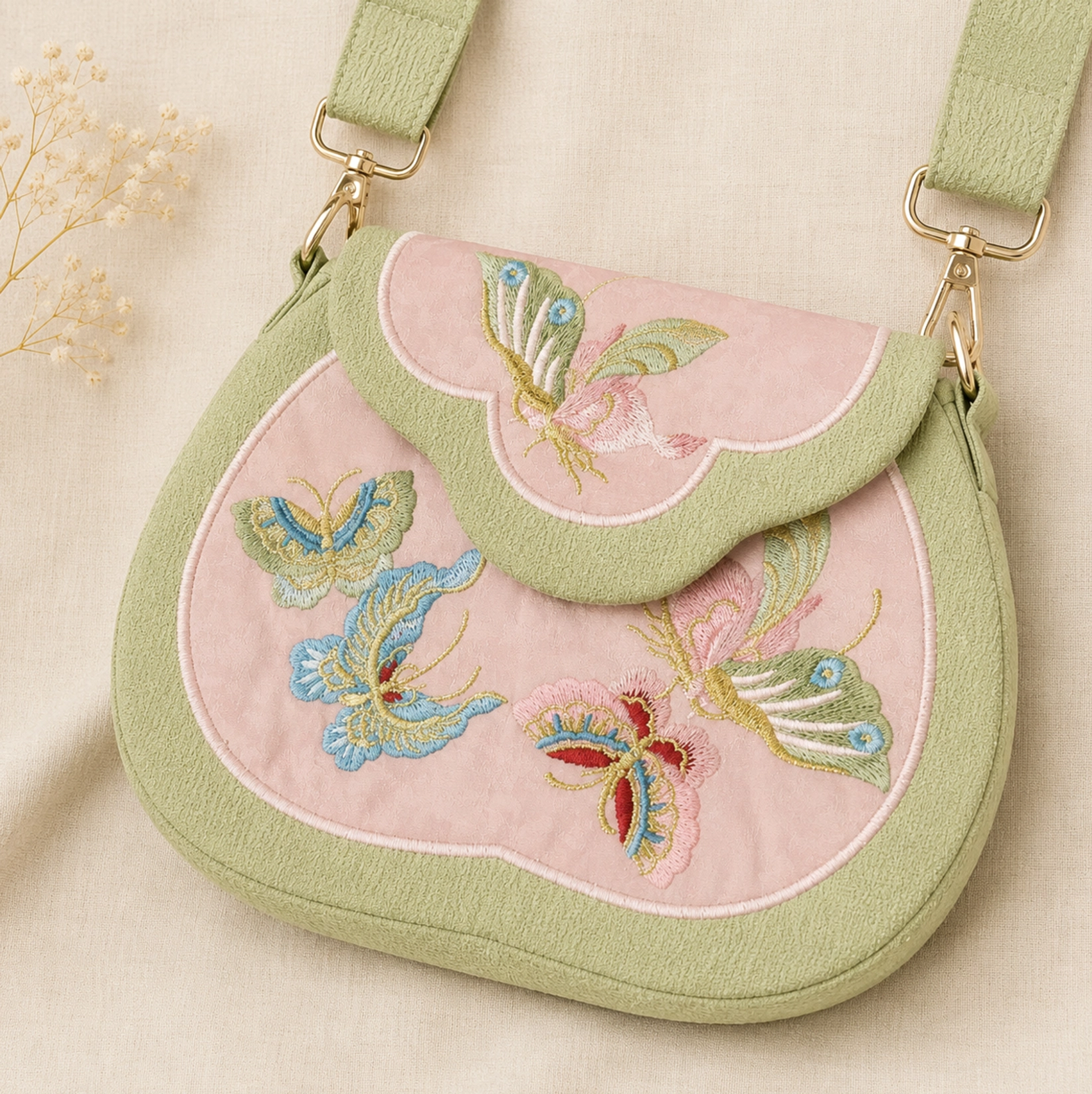 Tang-inspired butterfly embroidered Chinese crossbody bag in blush pink with sage green trim, cloud-shaped flap, gold-tone hardware and multicolor butterfly embroidery