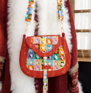 Tang-inspired lucky cat Chinese crossbody bag worn with a vintage winter coat showing adjustable shoulder strap and metal hardware