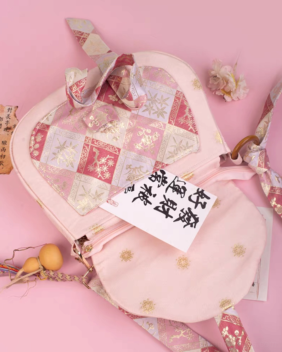 Open pink Hanfu crossbody bag showing gold dot printed lining, zippered compartment, and textured jacquard patchwork exterior