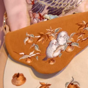 Close-up of sparrow persimmon and maple leaf embroidery on Tang-inspired Chinese crossbody bag with textured brown flap