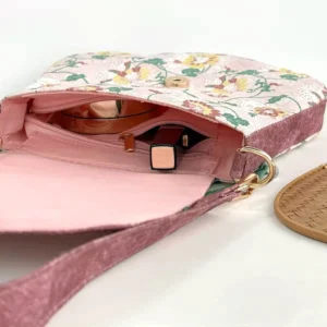 Interior of Tang-inspired floral Chinese crossbody bag showing pink lining metal snap closure and inner zipper pocket with cosmetics