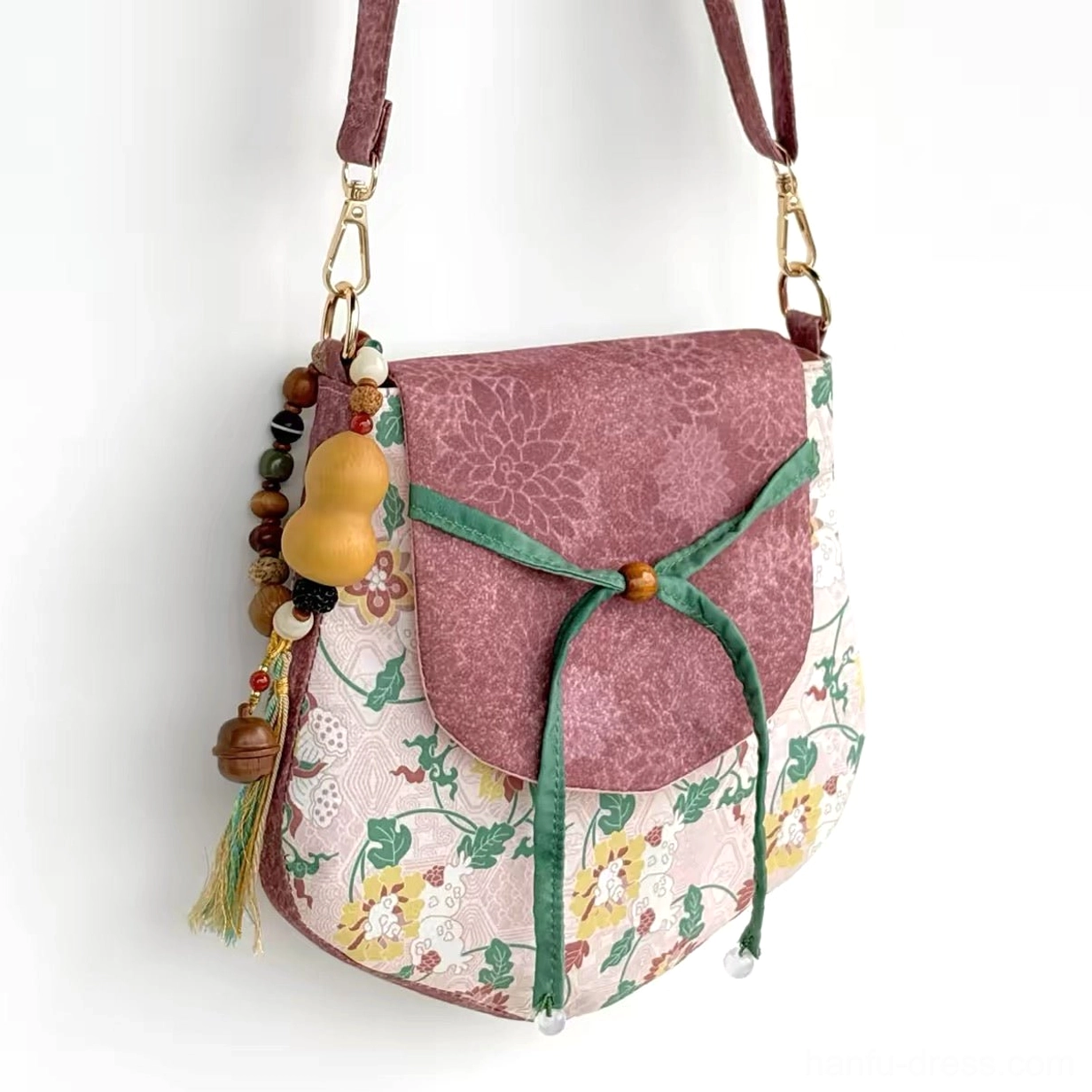 Three-quarter view of spring garden floral Chinese crossbody bag with mauve textured flap gold-tone hardware and gourd tassel charm