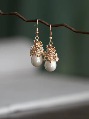 Vintage gold flower and teardrop pearl Chinese earrings for Hanfu against a soft neutral background
