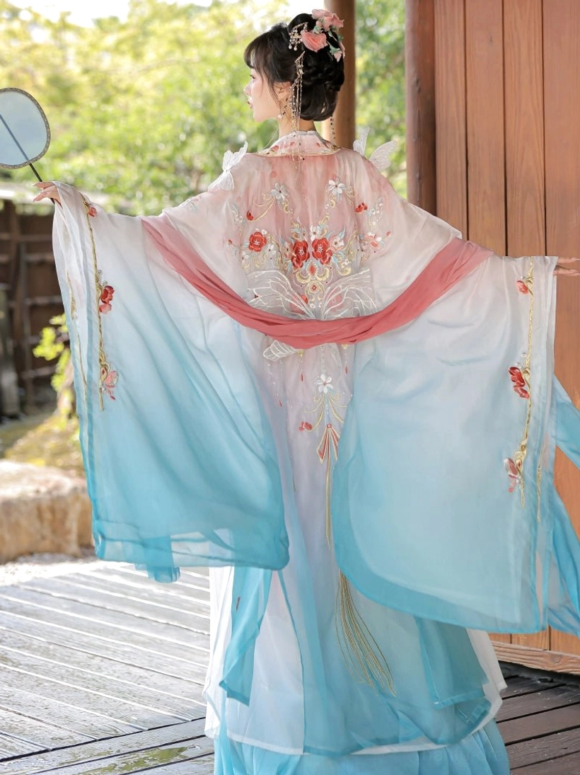 Tang style Hanfu Heziqun dress shown from the back with cyan white gradient sleeves, pink embroidery, red sash, and silk fan