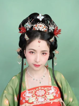 Female model wearing a Tang-style Hanfu outfit with a green shawl, red embroidered dress, traditional Chinese hair accessories, and classic ancient-inspired makeup