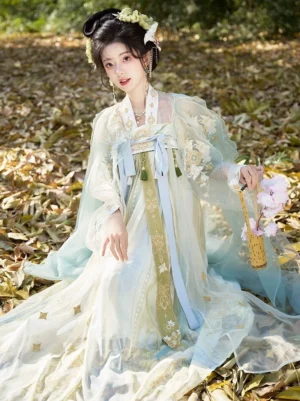 Seated model wearing Tang style Hanfu Qixiong Ruqun with cyan cloak, blue chest ribbons, golden embroidered cream skirt and traditional hair accessories