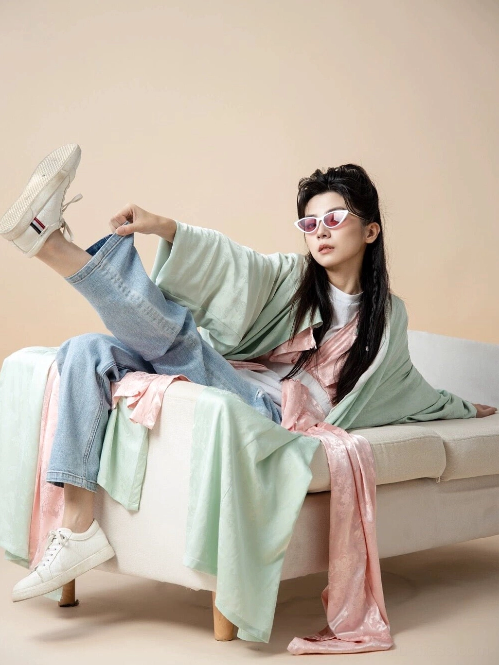Modern casual styling of a mint green Tang style Hanfu robe worn with peach pink layers denim jeans and white sneakers