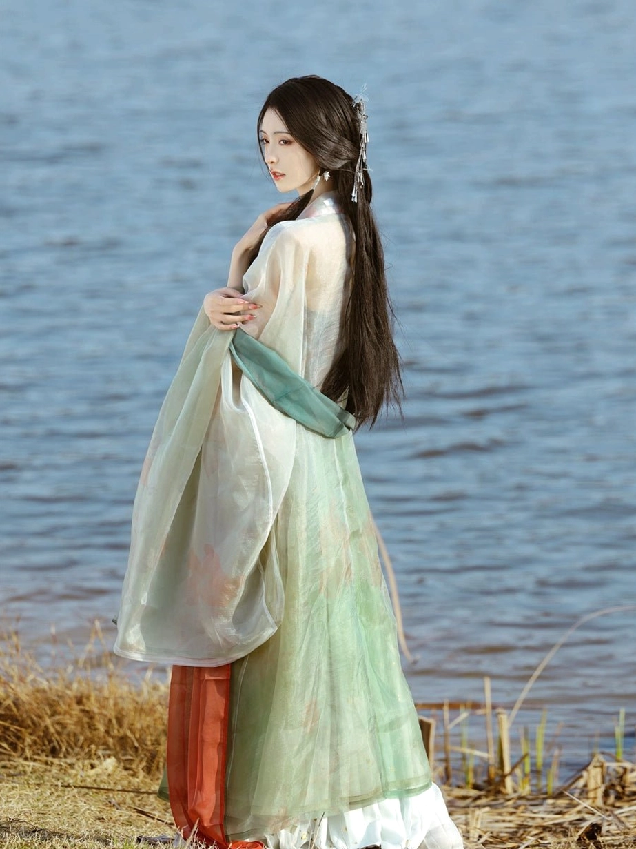 Back three-quarter view of Tang style Heziqun Hanfu with flowing green outer layers, cyan waist sash, red skirt accent, and white underskirt hem