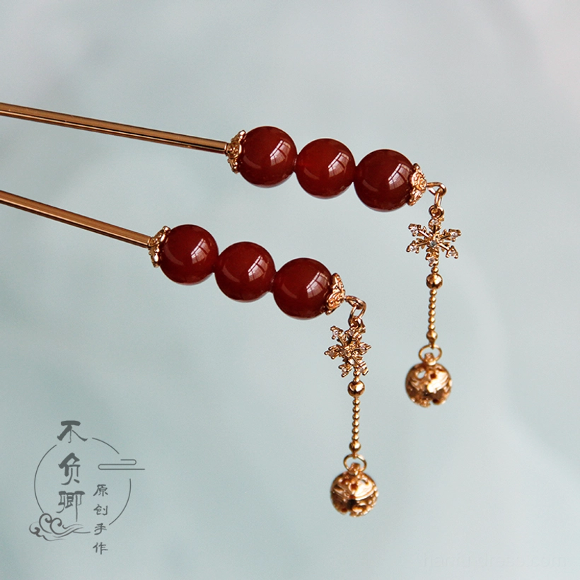 Tanghulu-style Chinese hair stick with three red beads gold-tone fitting snowflake charm and dangling bell tassel shown in horizontal view