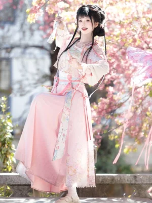 Pink xianxia modern hanfu set with floral embroidery, ruffled lantern sleeves and flowing waist ribbons in a cherry blossom courtyard