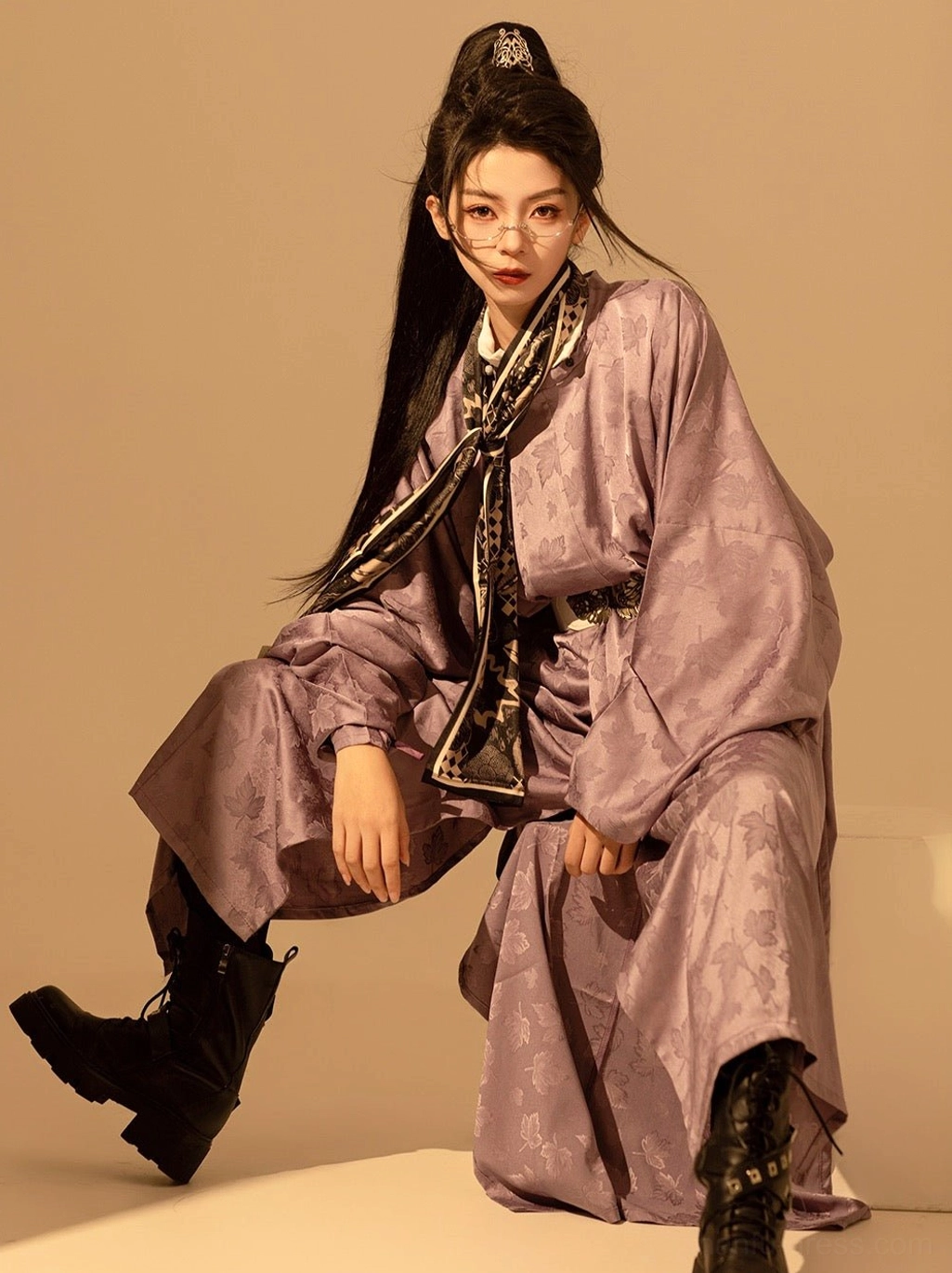 Side seated view of a flowing taro purple Tang-inspired Hanfu robe with wide sleeves, floor-length silhouette, glasses, and black combat boots