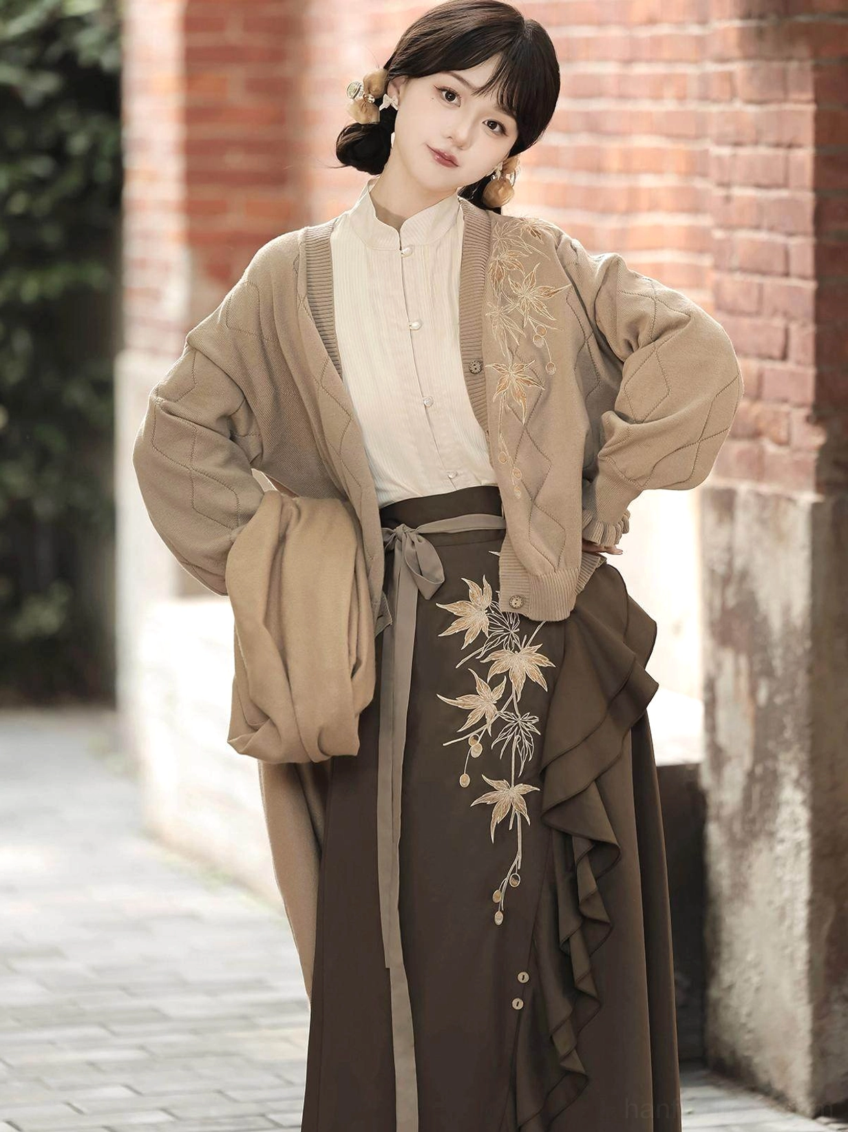 Close front view of a taupe rhombus knit cardigan with chest embroidery worn with a Chinese-inspired embroidered skirt and autumn scarf