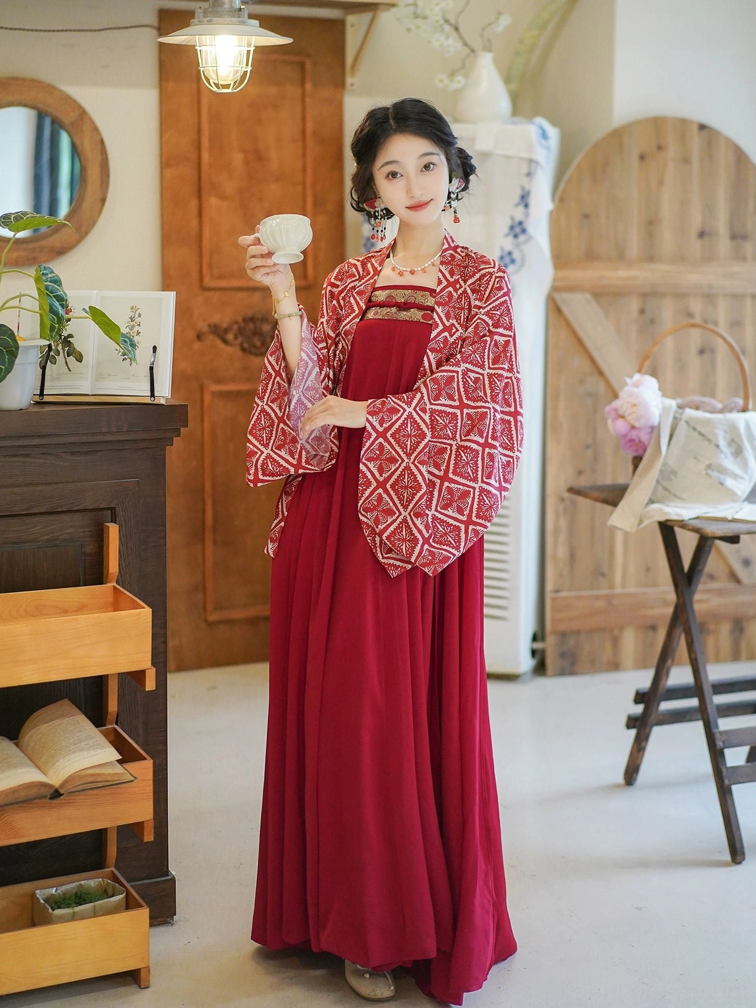 Full-body front view of a modern Tang Dynasty Hanfu outfit with a wine-red long dress and cropped wide-sleeve geometric print cardigan in a vintage cafe setting
