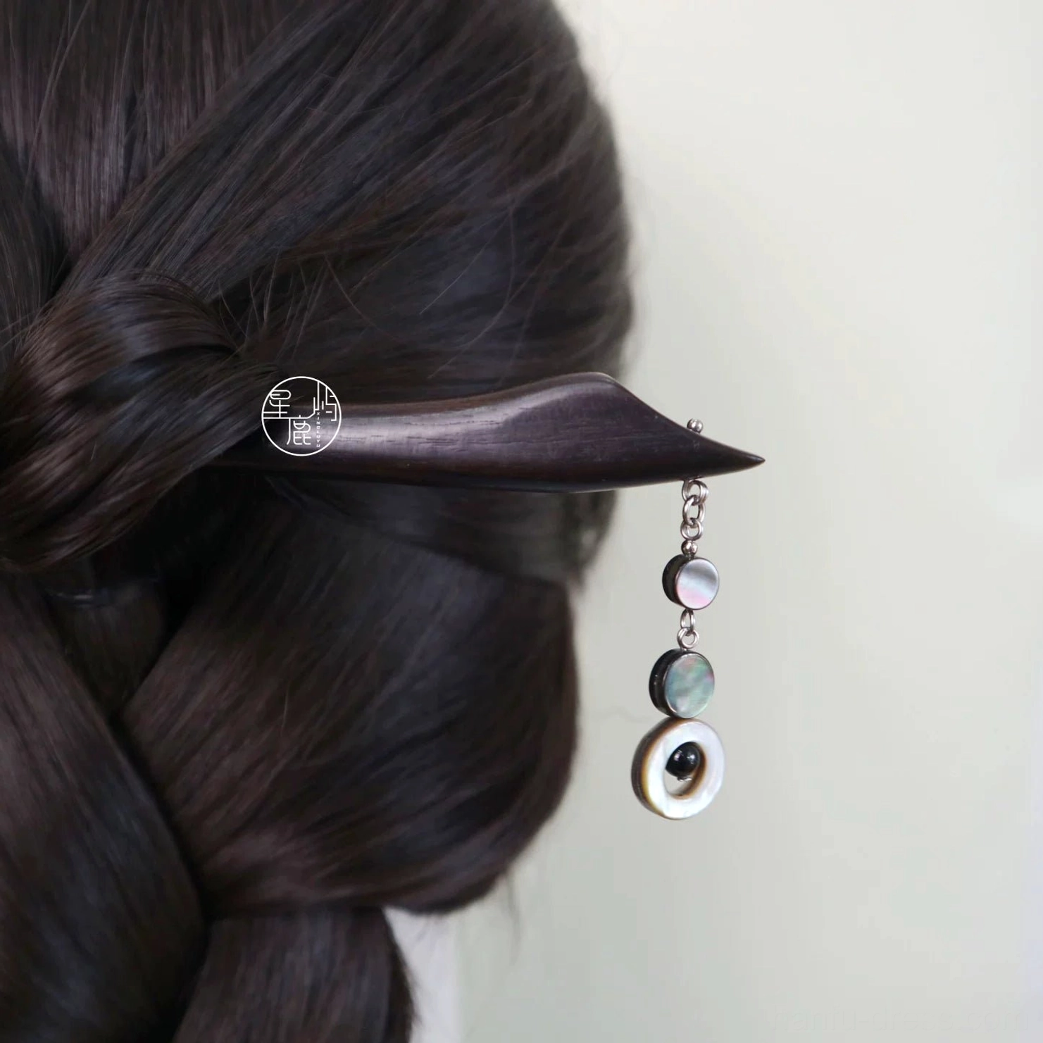 Traditional Chinese hair stick securing a braided Hanfu hairstyle with a shell tassel hanging naturally beside dark hair