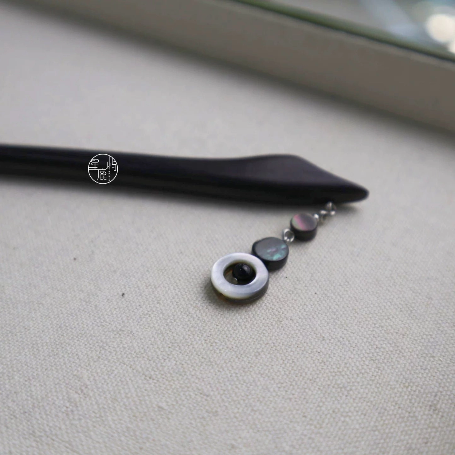 Full flat lay view of a dark wood Chinese hair stick with petal tip, beads, and complete shell tassel ornament