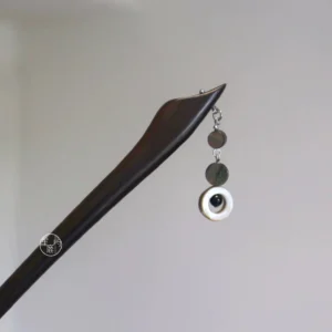 Dark wood Chinese hair stick with petal-shaped tip, shell drop, and traditional tassel ornament on a light gray background