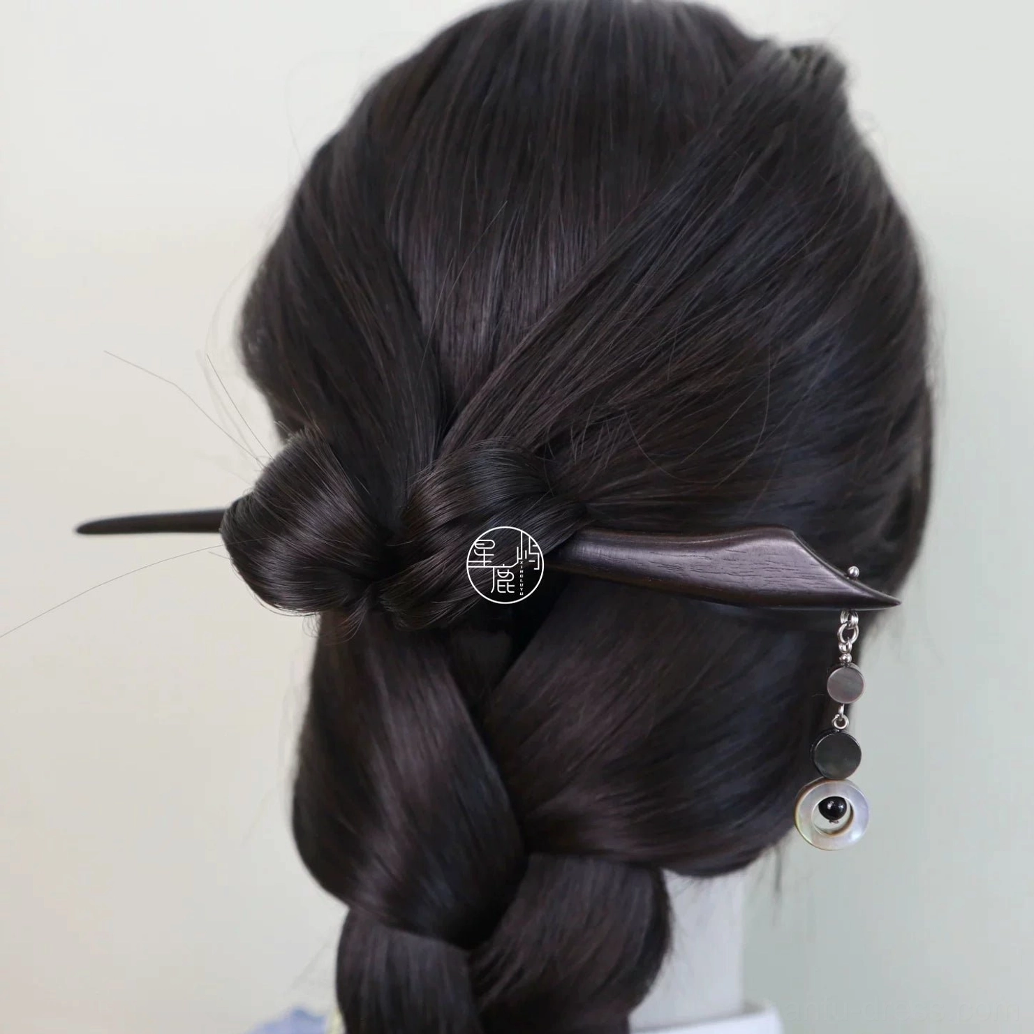 Dark wood Hanfu hair stick with shell tassel securely styled in a neat braided traditional Chinese updo