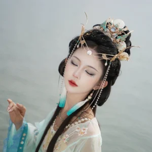 Side view of Tidal Sea Spirit Chinese Hanfu crown and forehead headdress on a model by calm water, with blue gradient tassel details and pearl-inspired hair jewelry