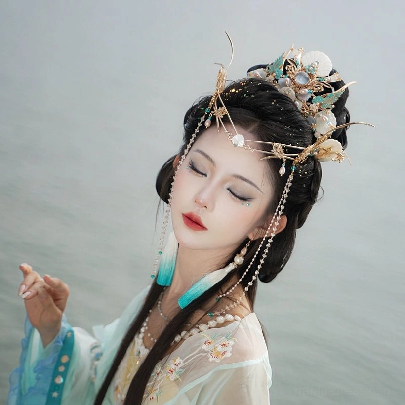 Side view of Tidal Sea Spirit Chinese Hanfu crown and forehead headdress on a model by calm water, with blue gradient tassel details and pearl-inspired hair jewelry
