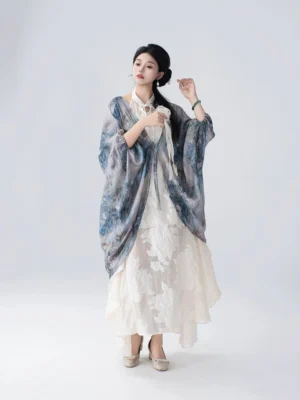 Woman with a traditional-inspired updo wearing a tie-front Chinese-style cardigan layered over a flowing off-white dress with a ruffled hem