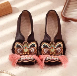 Overhead view of black tiger-head embroidered traditional Chinese Hanfu shoes with colorful face details, imitation pearl decorations, pink tassel whiskers, fluffy furry toe trim, and breathable textile insoles