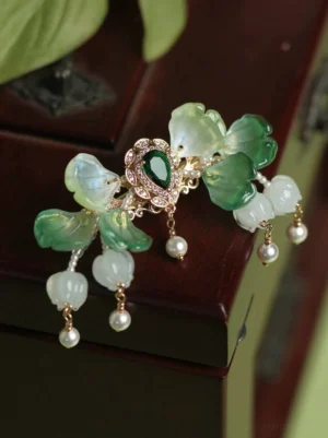 Side view of green Chinese Hanfu back hair pin featuring translucent green-white flower petals, gold-tone details, glass tassels, and pearl-like pendants