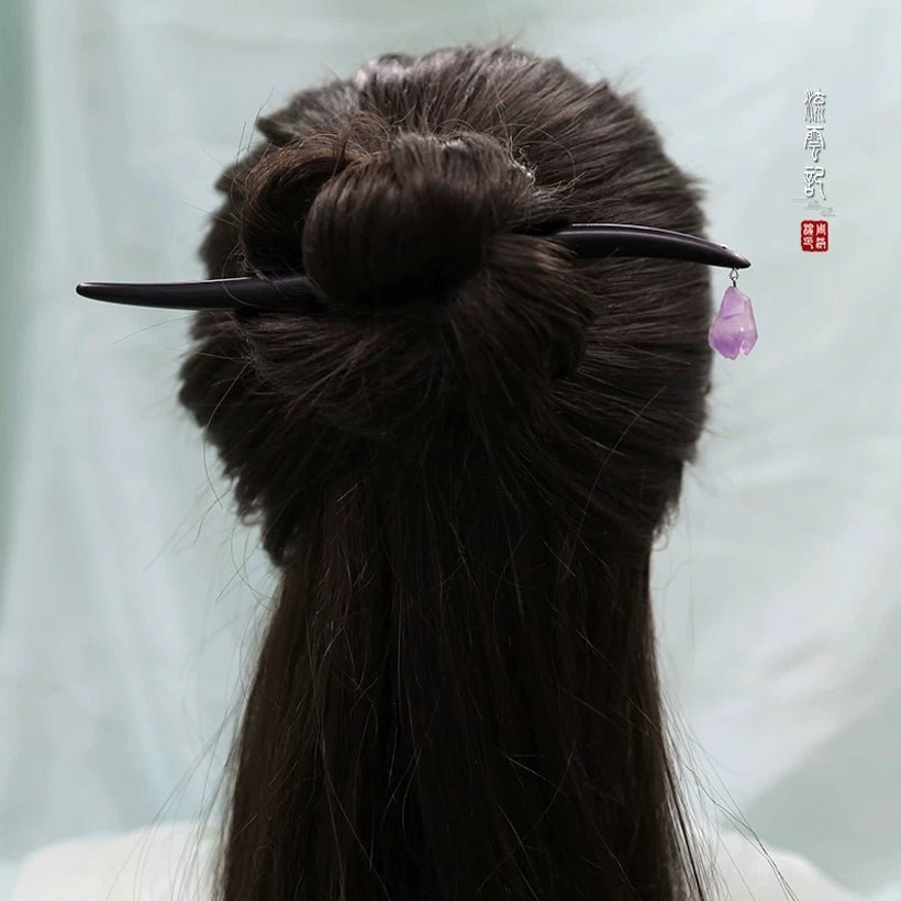 Close back wearing view of traditional black wooden Chinese hair stick with amethyst charm in a neat dark hair bun