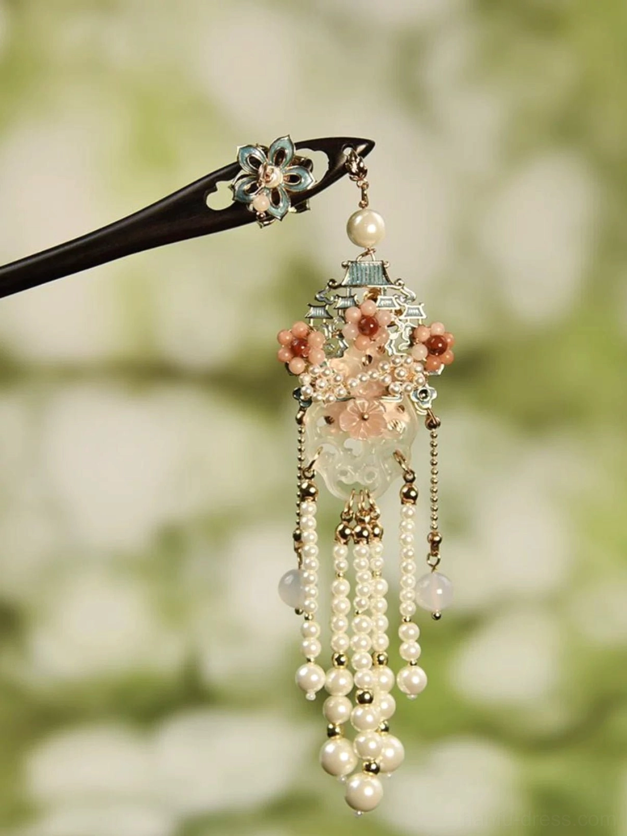 Traditional black wooden Chinese hair stick with floral enamel ornament, pink flower pendant, hollow carved jade-inspired charm, and layered pearl tassels in a soft green setting
