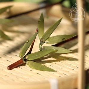 Traditional Chinese bamboo hairpin with reddish brown stem, glossy green leaves, and water drop embellishments